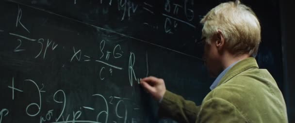 Starý profesor nebo vědec pracující, psaní postav s křídou na tabuli
