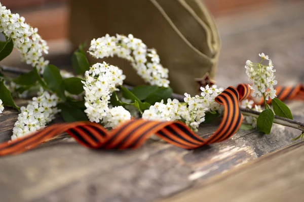 9 Mayıs zafer günü geçmişi. Bahar çiçekleri kiraz ağaçları, askeri şapkalar, St. George kurdelesi. 1945 Zafer Günü 'nün geleneksel sembolü Tebrik kartı tasarımı.