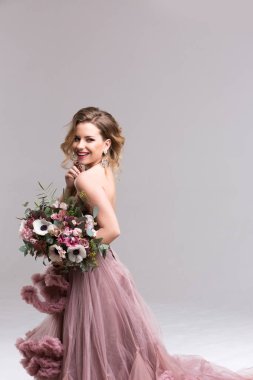 Pembe elbise ve düğün çiçekleri uzun kıvırcık saçlı güzel genç kız.