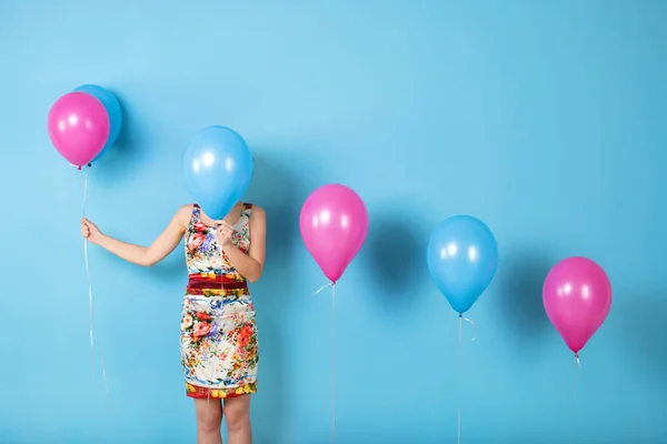 Žena a helium balónky na modrém pozadí. — Stock fotografie