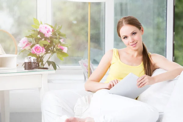 Happy woman with tablet on couch.