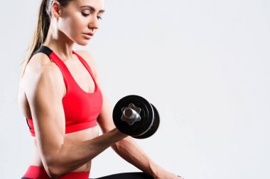 Atletik kadın fitness egzersiz gri arka plan üzerinde dumbbells ile yapıyor.