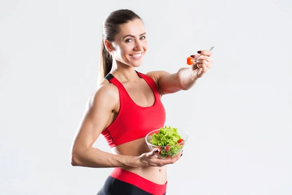 Schöne lächelnde Frau isst Salat mit Gabel, isoliert. — Stockfoto