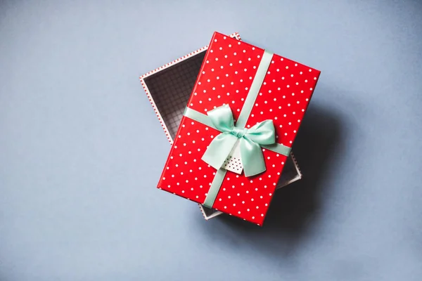 Ανοιχτό κόκκινο δώρο με φιόγκο σε μπλε φόντο το top view. — Φωτογραφία Αρχείου