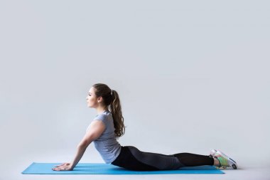 Genç güzel yoga gri arka plan üzerinde poz.