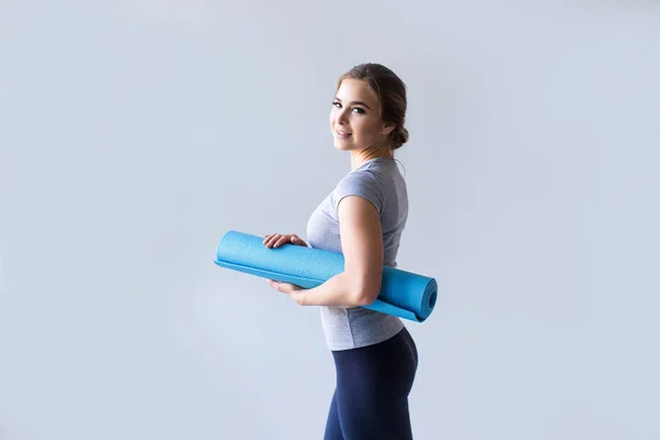 Yoga mat gri arka plan üzerinde kadınla Fitness. — Stok fotoğraf