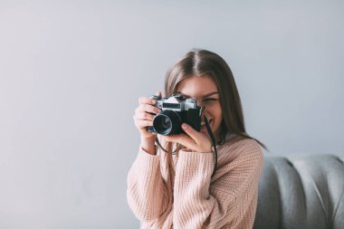 Evde fotoğraf makinesi ile yüzünü kaplayan portre kadın fotoğrafçı.