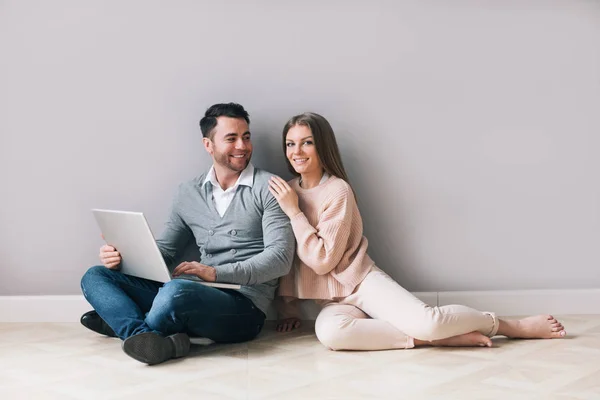 Feliz pareja de compras en línea en el ordenador portátil mientras se sienta piso . — Foto de Stock