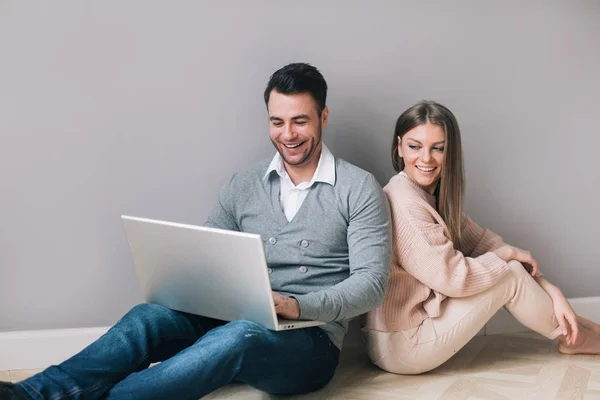 Pareja con portátil sonriendo sentada en el suelo . — Foto de Stock