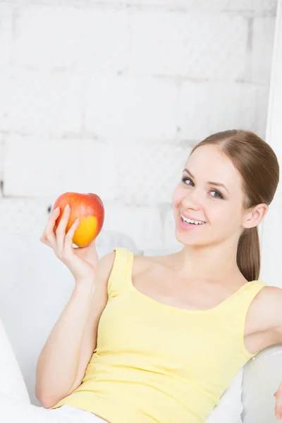 Beautiful girl with apple sitting at home. — Stock Photo, Image