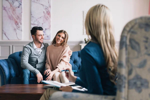 Hermosa y feliz joven pareja visitando psicólogo para el asesoramiento de relaciones . — Foto de Stock