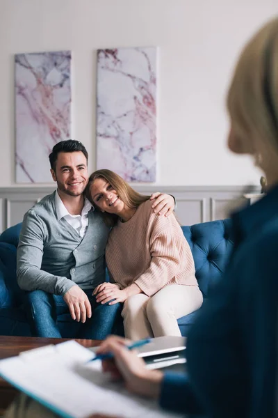 Hermoso joven marido y mujer están visitando a un psicólogo. Sentarse y abrazar . — Foto de Stock