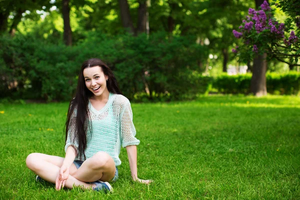 Usmívající se krásná mladá žena seděla na trávě. — Stock fotografie