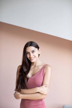 Uzun saçlı güzel bir kadın duvarın arkasında gülümsüyor.