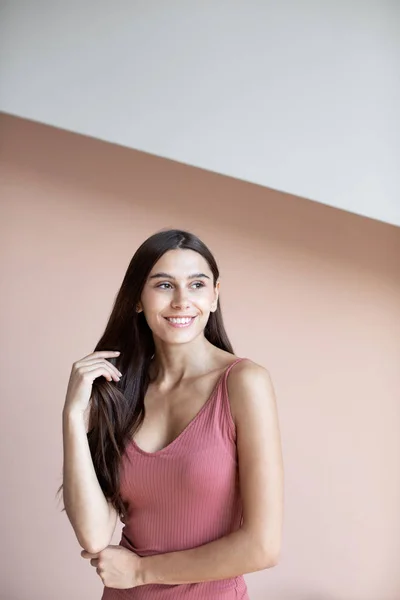 Schöne Frau mit langen Haaren lächelt drinnen auf Wandbackgr — Stockfoto