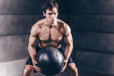 Atletizm sporcusu, jide bir tıp topuyla duvar topu atışı yapıyor.