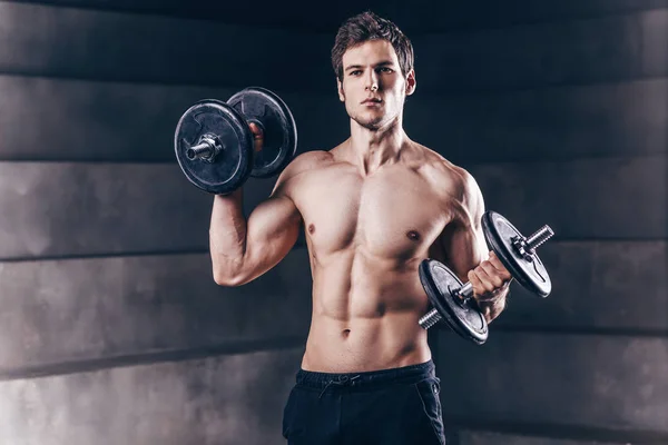 Un hombre musculoso atractivo posando con mancuerna. Instruc fitness —  Fotos de Stock