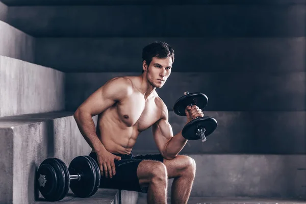 Strong muscle man sit and exercise biceps with heavy dumbbells. — 스톡 사진
