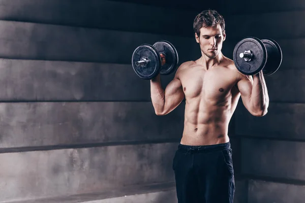 Hombre musculoso guapo en pantalones cortos, haciendo ejercicios con mancuerna , — Foto de Stock