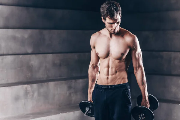 Hombre musculoso fuerte posando con mancuerna . — Foto de Stock