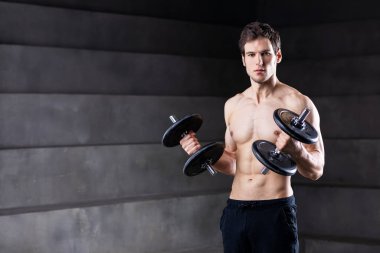 Şortlu yakışıklı kaslı adam, halterle egzersiz yapıyor., 
