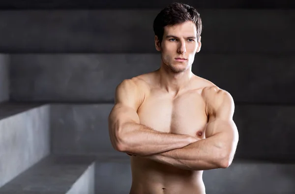 Portrait of a muscular handsome bodybuilder standing with crosse — Stock Photo, Image