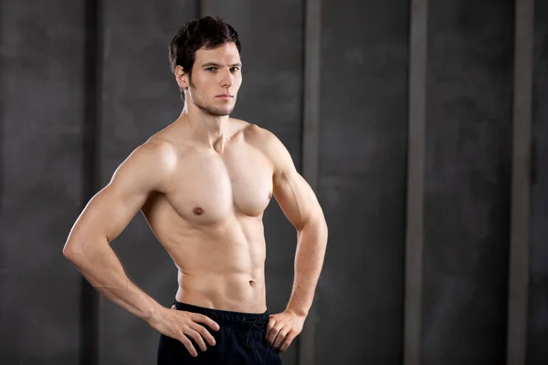 Un joven musculoso en un estudio. Retrato de un tipo fuerte y brutal —  Fotos de Stock