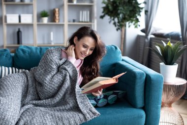 Evdeki rahat bir kanepede kitap okuyan güzel bir kadın.. 