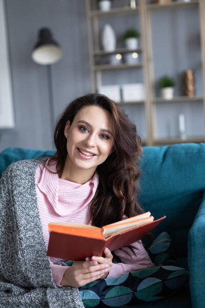 Happy young woman reading she holds book in hands. 