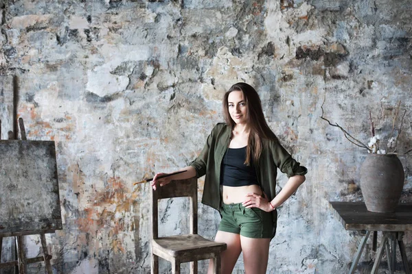 Young smiling brunette woman artist holding a brush in studio. — Stock Photo, Image