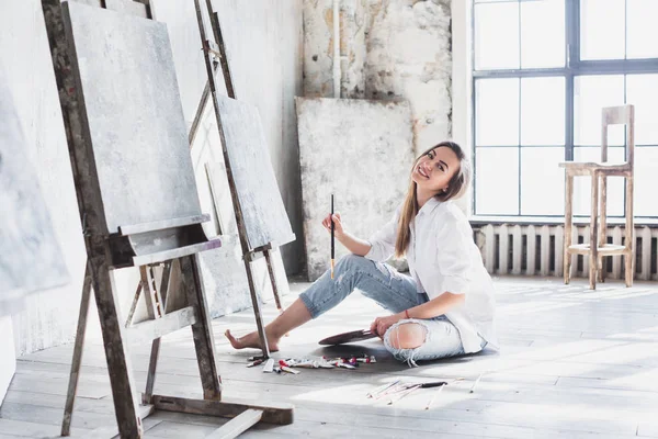 Portret van jonge vrouw schilderen met borstel in studio. — Stockfoto