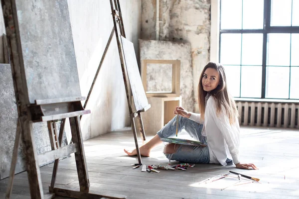Flickkonstnär ritar i en konststudio. Kvinnan på golvet. — Stockfoto