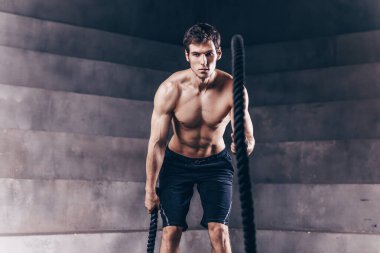 Yakışıklı kaslı adam spor yaparken halat egzersizi yapıyor. Kuvvet ve motivasyon.