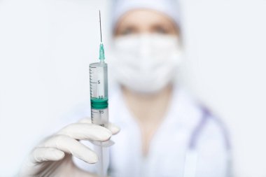Tıbbi koruyucu maskeli, şırıngayla yakından çekilmiş bir kadın doktor. Virüs için aşı.