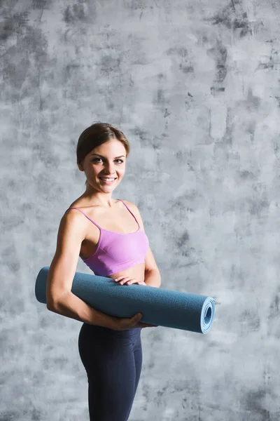 年轻的微笑的女人带着瑜伽垫 室内女运动员的画像 — 图库照片