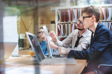 Masadaki bir ofiste çalışan insanlar modern başlangıç ofisindeki yaratıcı sürdürülebilir fikirlere katılıyorlar. Eş çalışma.