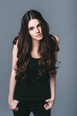 Gri arka planda siyah giyinmiş hoş bir genç kadın..