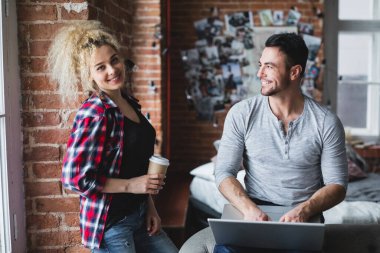 Laptopları olan ve modern evde kahve içen güzel bir çift. Web sörfü.