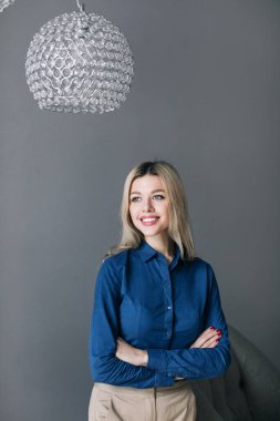 Gri arka planda duran neşeli iş kadını. Bir ofis çalışanının portresi..