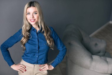 Gri arka planda duran neşeli iş kadını. Bir ofis çalışanının portresi..