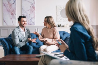 Psikolojik danışmanlık. Terapi sırasında psikolog dinleyen çift evdeki kanepede oturuyor..