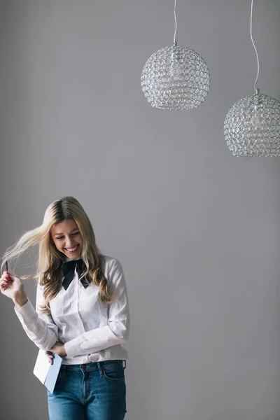Śmiejąca Się Blondynka Dżinsach Biała Koszula Stojąca Przy Ścianie Notatnikiem — Zdjęcie stockowe