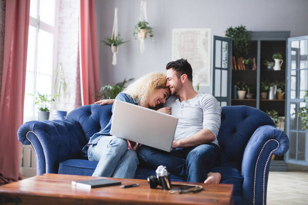 Joyful couple with a laptop at home. Choose online.