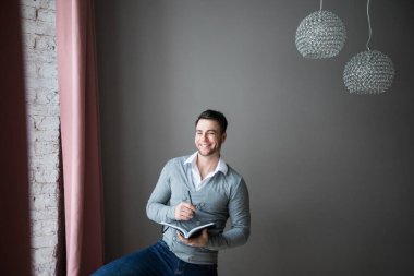 Evde elinde defter ve kalemle gülümseyen adam. Düşüncelerini yaz..