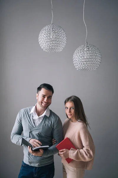 Two students, a man and a woman with notebooks, are looking at the camera. Education.