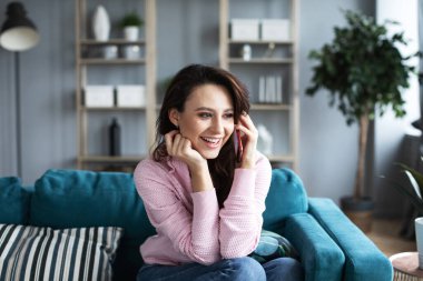 Evdeki kanepede otururken telefonda konuşan güzel bir kadın. Akıllı telefondan ara..