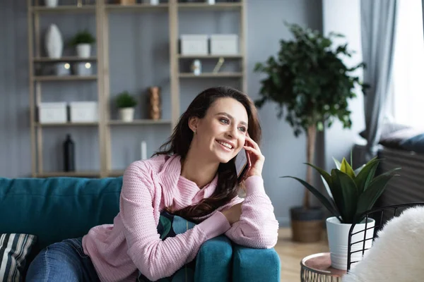 Szczęśliwa Młoda Kobieta Rozmawiająca Przez Telefon Siedząca Wygodnej Kanapie Domu — Zdjęcie stockowe