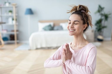 Genç, sakin, gülümseyen yogi kadının portresi. Yoga yapıyor, oturuyor ve gözleri kapalı meditasyon yapıyor. Rahatlıyorum..