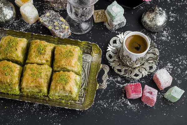 传统的土耳其糕点Pistachio Baklava 放在有咖啡和欢乐的老式托盘上 图库图片