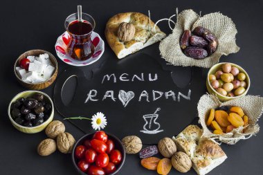 Traditional Turkish Ramadan iftar foods around of handwriting Menu Ramadan on the black surface.Top view